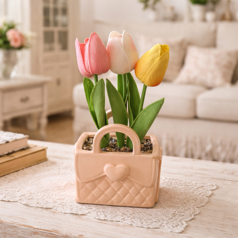 Bomboniera a forma di borsetta in ceramica color pesca con trama trapuntata e cuore, contenente tre tulipani artificiali rosa, bianco e giallo.